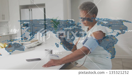 Measuring senior woman using blood pressure monitor and smartphone at kitchen island Measuring senior woman using blood pressure monitor and smartphone at kitchen island 135321252