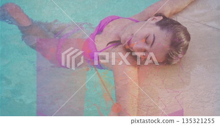 Reclining woman wearing pink bikini dipping into turquoise swimming pool water on stone deck Reclining woman wearing pink bikini dipping into turquoise swimming pool water on stone deck 135321255