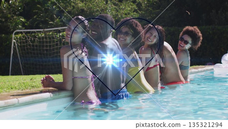 Friends in swimsuits leaning at backyard pool, holding smartphone with heart lens flare effect 135321294