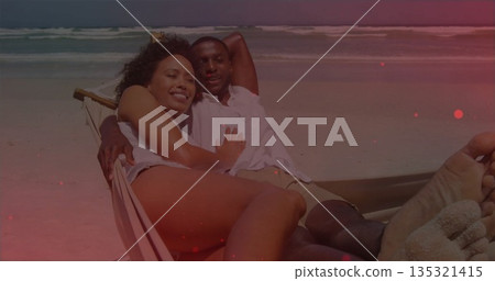 Lying couple wearing summer clothing on hammock lounger at sandy beach, ocean waves rolling Lying couple wearing summer clothing on hammock lounger at sandy beach, ocean waves rolling 135321415