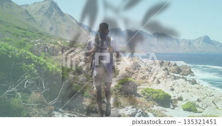 Adjusting backpack straps, male hiker navigating rocky coastal trail, with sunglasses face mask 135321451