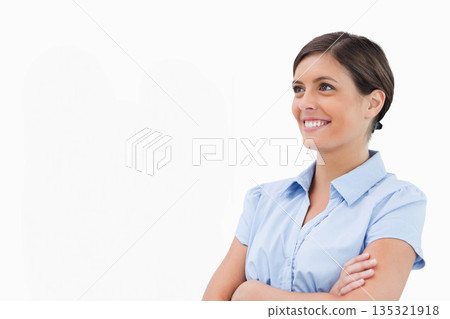 Woman standing smiling with arms crossed in studio wearing light blue collared shirt, copy space 135321918