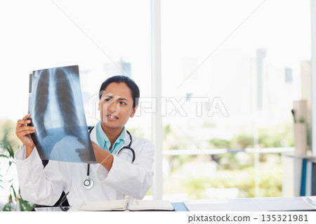 Indian woman doctor examining chest X-ray film in white lab coat at clinic desk with stethoscope 135321981