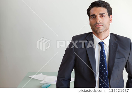 Mid adult man in suit standing at office desk reviewing papers and checking smartphone, copy space Mid adult man in suit standing at office desk reviewing papers and checking smartphone, copy space 135321987