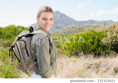 Female hiker standing in foothills wearing olive-green jacket, carrying backpack, copy space Female hiker standing in foothills wearing olive-green jacket, carrying backpack, copy space 135322021