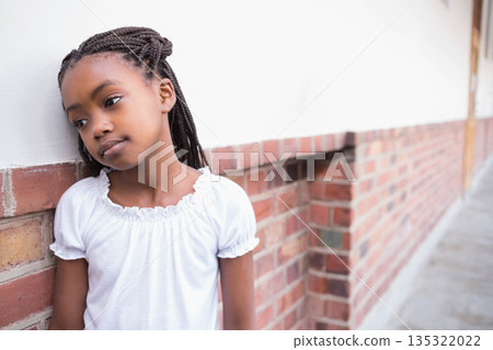 African American child girl standing next to brick wall on sidewalk with long braids, copy space 135322022