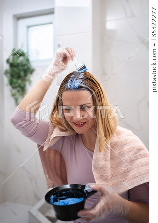Woman applying blue hair dye at home Woman applying blue hair dye at home 135322277