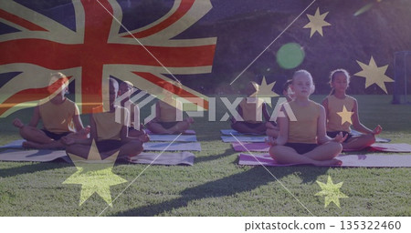 Eight children wearing yellow tops practicing lotus pose in grass field, with mats and flag overlay 135322460