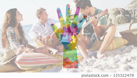 Group wearing swimwear chatting, listening to guitar on beach by outcrop, with picnic basket Group wearing swimwear chatting, listening to guitar on beach by outcrop, with picnic basket 135322479