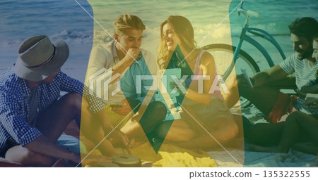Sitting friends wearing straw hat sharing snacks on beach blanket, with tablet bicycle beverage can Sitting friends wearing straw hat sharing snacks on beach blanket, with tablet bicycle beverage can 135322555