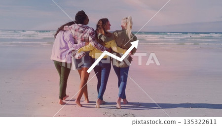 Walking women wearing jackets linking arms on beach, barefoot feet, ocean waves and graph overlay 135322611