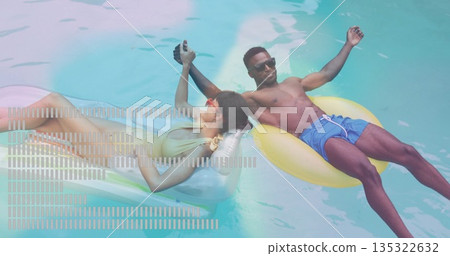 Floating couple holding hands on yellow and silver rings in pool, wearing swimwear and sunglasses Floating couple holding hands on yellow and silver rings in pool, wearing swimwear and sunglasses 135322632