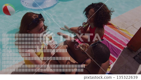 Relaxing three women in swimsuits dipping legs in pool at backyard pool deck, with wine glasses 135322639