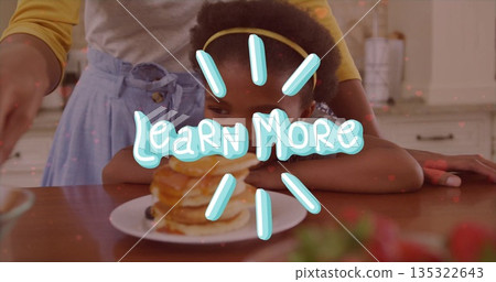 Serving pancakes mother and daughter sharing meal at kitchen counter, with spatula and strawberries 135322643