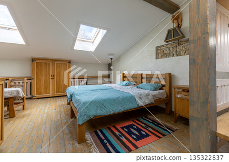 Cozy rustic attic bedroom with wooden bed and skylights 135322837