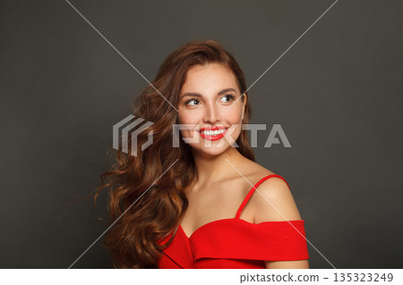 Posing woman with long hair and make-up on black background. Gorgeous woman with curly hairstyle 135323249