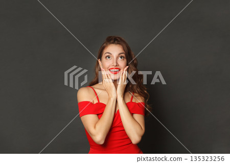 Cute surprised woman with curly hairstyle and makeup holding her hand with her face Cute surprised woman with curly hairstyle and makeup holding her hand with her face 135323256
