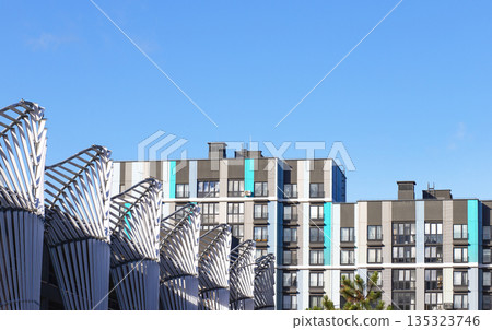 Modern residential apartment buildings with gray, white, and turquoise vertical accents, seen behind 135323746