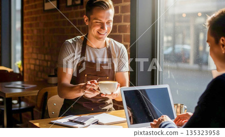 A Barista Smiling Warmly While Handing a Fresh Coffee to a Lone Worker in a Cozy Cafe Setting 135323958