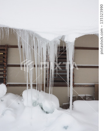 Icicles hanging from the eaves of a snowy country - Image of winter ice Icicles hanging from the eaves of a snowy country - Image of winter ice 135323990