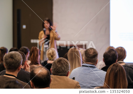 Speaker presenting to engaged audience at conference with microphone and projection screen Speaker presenting to engaged audience at conference with microphone and projection screen 135324050