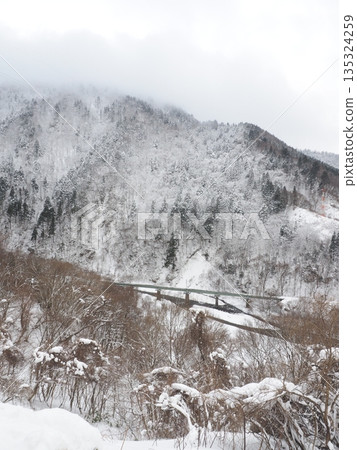 Railway tracks visible among snowy mountains. Winter scenery like a sumi-e painting. Copy space. Railway tracks visible among snowy mountains. Winter scenery like a sumi-e painting. Copy space. 135324259