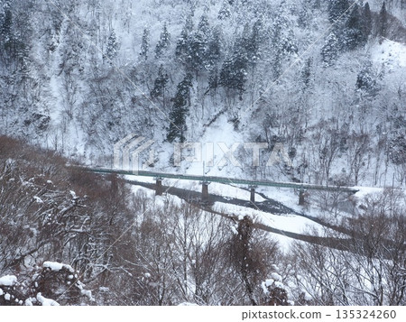 Railway tracks visible among snowy mountains. Winter scenery like a sumi-e painting. Copy space. Railway tracks visible among snowy mountains. Winter scenery like a sumi-e painting. Copy space. 135324260
