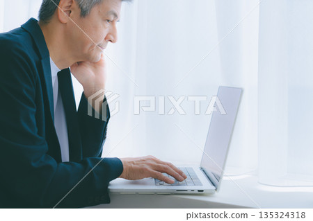 A man working on a computer by the window 135324318