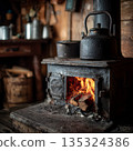 Close-up of iron potbelly stove with fire inside, kettle on top, rustic wooden walls around 135324386