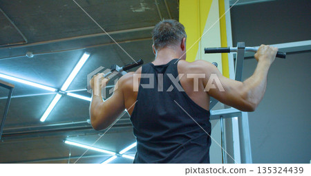 Pull-ups. Middle aged Caucasian man trains his back muscles in the gym. Middle-aged Caucasian man trains back with precise form during an intense gym workout. Gym workout - back exercise. Pull-ups. Middle aged Caucasian man trains his back muscles in the gym. Middle-aged Caucasian man trains back with precise form during an intense gym workout. Gym workout - back exercise. 135324439