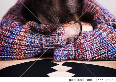 Depressed woman hiding face in arms near a broken black heart. Sad lonely female suffering from a breakup. Anti-Valentine's Day concept. High quality photo Depressed woman hiding face in arms near a broken black heart. Sad lonely female suffering from a breakup. Anti-Valentine's Day concept. High quality photo 135324802