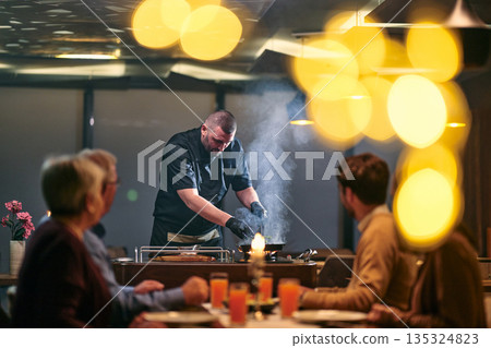 Professional Restaurant Chef Cooking Meat with Flambe Technique at Table for Guests Professional Restaurant Chef Cooking Meat with Flambe Technique at Table for Guests 135324823