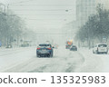 Heavy snowfall cover urban street Magdeburg car service truck move low visibility icy condition. Winter storm tram wire snow fill air traffic jam danger transport disruption harsh weather impact 135325983