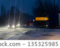 Night winter road Magdeburg heavy snowfall cars truck driving icy junction illuminated headlights streetlight. Direction sign low visibility snow covered asphalt traffic danger transport challenge 135325985