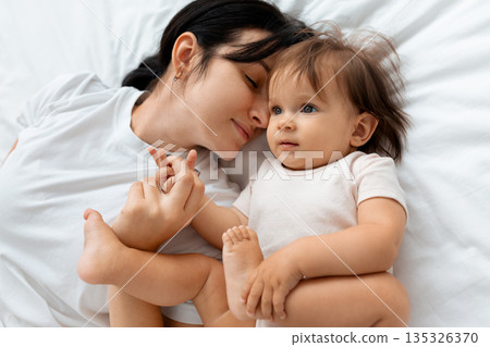 Mother lying close to her infant baby on bed at home Mother lying close to her infant baby on bed at home 135326370