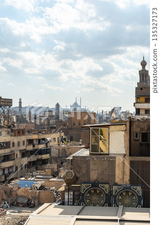 A panoramic view of Old Cairo in Egypt showcases historic buildings, minarets, and rooftops under a cloudy sky. The scene reflects the rich architectural heritage of the city. A panoramic view of Old Cairo in Egypt showcases historic buildings, minarets, and rooftops under a cloudy sky. The scene reflects the rich architectural heritage of the city. 135327173