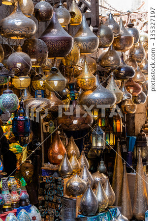 Khan el-Khalili market in Cairo features vibrant stalls filled with colorful goods. Diverse people browse the market, surrounded by traditional architecture and lively atmosphere. Khan el-Khalili market in Cairo features vibrant stalls filled with colorful goods. Diverse people browse the market, surrounded by traditional architecture and lively atmosphere. 135327197