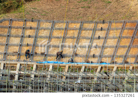 Workers securing slopes while attached to ropes for safety 135327261