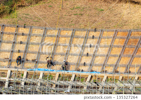 Workers securing slopes while attached to ropes for safety 135327264