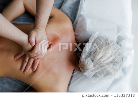 Therapist performing deep tissue back massage on woman Therapist performing deep tissue back massage on woman 135327318