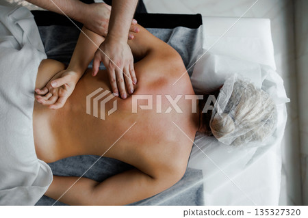 Therapist performing deep tissue back massage on woman Therapist performing deep tissue back massage on woman 135327320