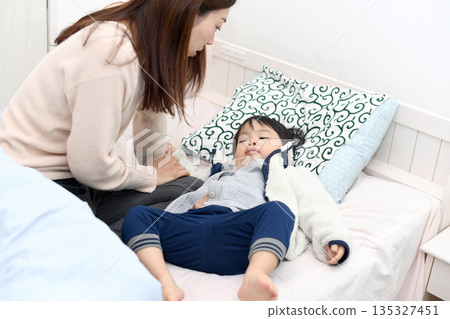 Asian mother putting her baby boy to bed Asian mother putting her baby boy to bed 135327451