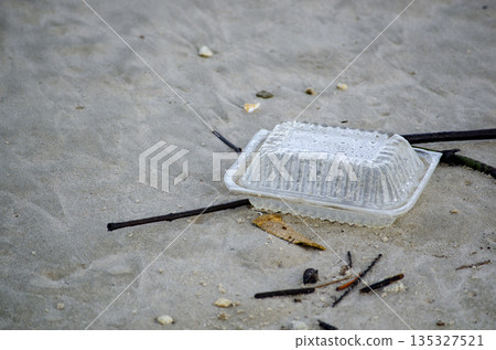 Transparent plastic container thrown on pavement representing plastic waste impact on urban environment Transparent plastic container thrown on pavement representing plastic waste impact on urban environment 135327521