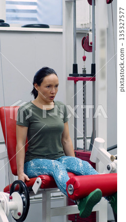 Dedicated to fitness, the woman steadily completes leg extensions, emphasizing controlled movements and muscle engagement for optimal results. Slow motion 4k footage. Dedicated to fitness, the woman steadily completes leg extensions, emphasizing controlled movements and muscle engagement for optimal results. Slow motion 4k footage. 135327577