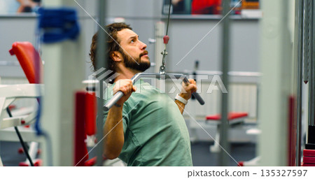 A Caucasian man working out in the gym. Workout for back muscles. Physical education as a norm of life for maintaining health. A Caucasian man working out in the gym. Workout for back muscles. Physical education as a norm of life for maintaining health. 135327597