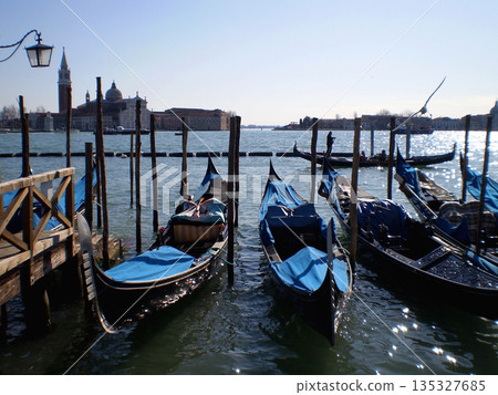 A picturesque view of traditional gondolas on the canals of Venice, Italy. The scene highlights elegant black boats, calm water reflections, and historic Venetian architecture, capturing the timeless A picturesque view of traditional gondolas on the canals of Venice, Italy. The scene highlights elegant black boats, calm water reflections, and historic Venetian architecture, capturing the timeless 135327685