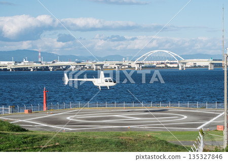 A small helicopter landing at a heliport on the Osaka Bay coast and a view of Konohana Bridge (Air Mobility) A small helicopter landing at a heliport on the Osaka Bay coast and a view of Konohana Bridge (Air Mobility) 135327846
