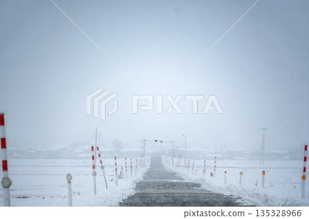 暴風雪中積雪覆蓋的道路和路標 暴風雪中積雪覆蓋的道路和路標 135328966