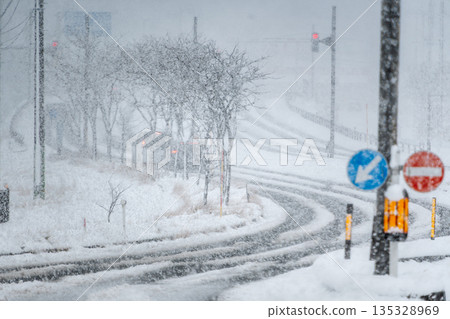 Snowstorm intersection and cars passing by 135328969