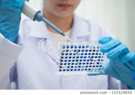 Scientist with cell culture in sample micro plate for research in science laboratory. Scientist with cell culture in sample micro plate for research in science laboratory. 135329856